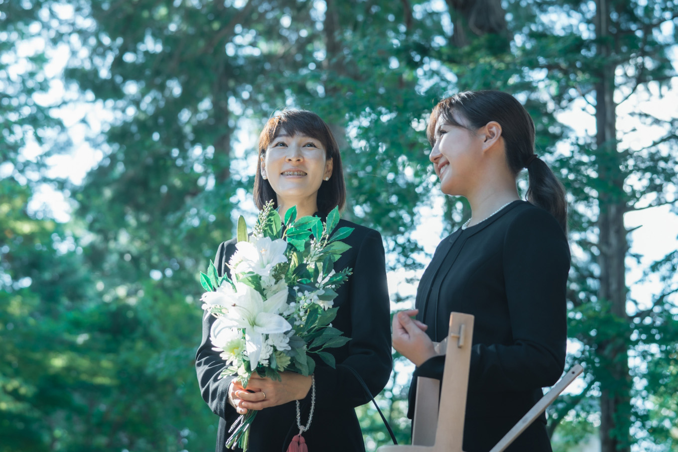 葬儀に列席している花束を抱えた女性